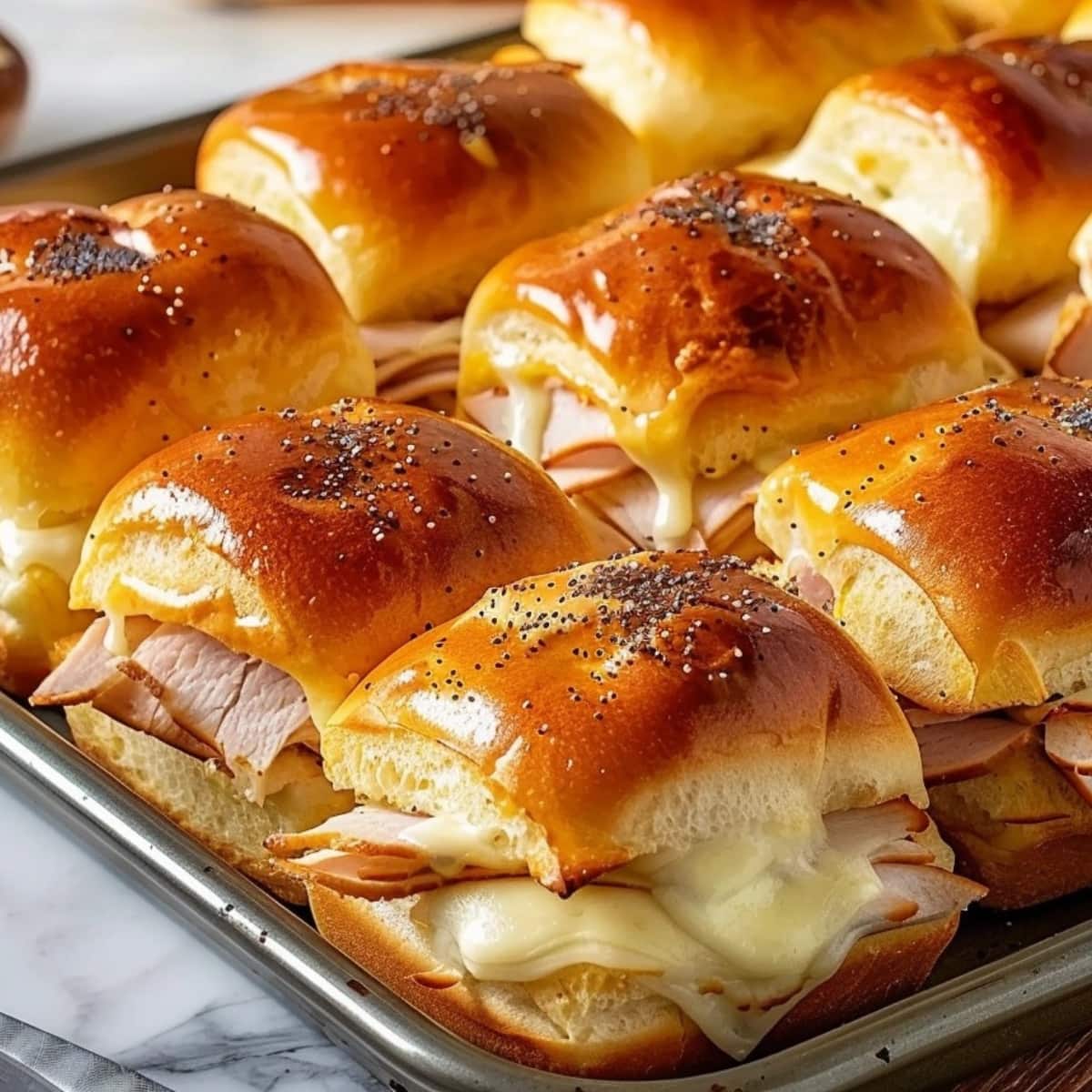 Turkey and cheese sliders arranged on a sheet pan.
