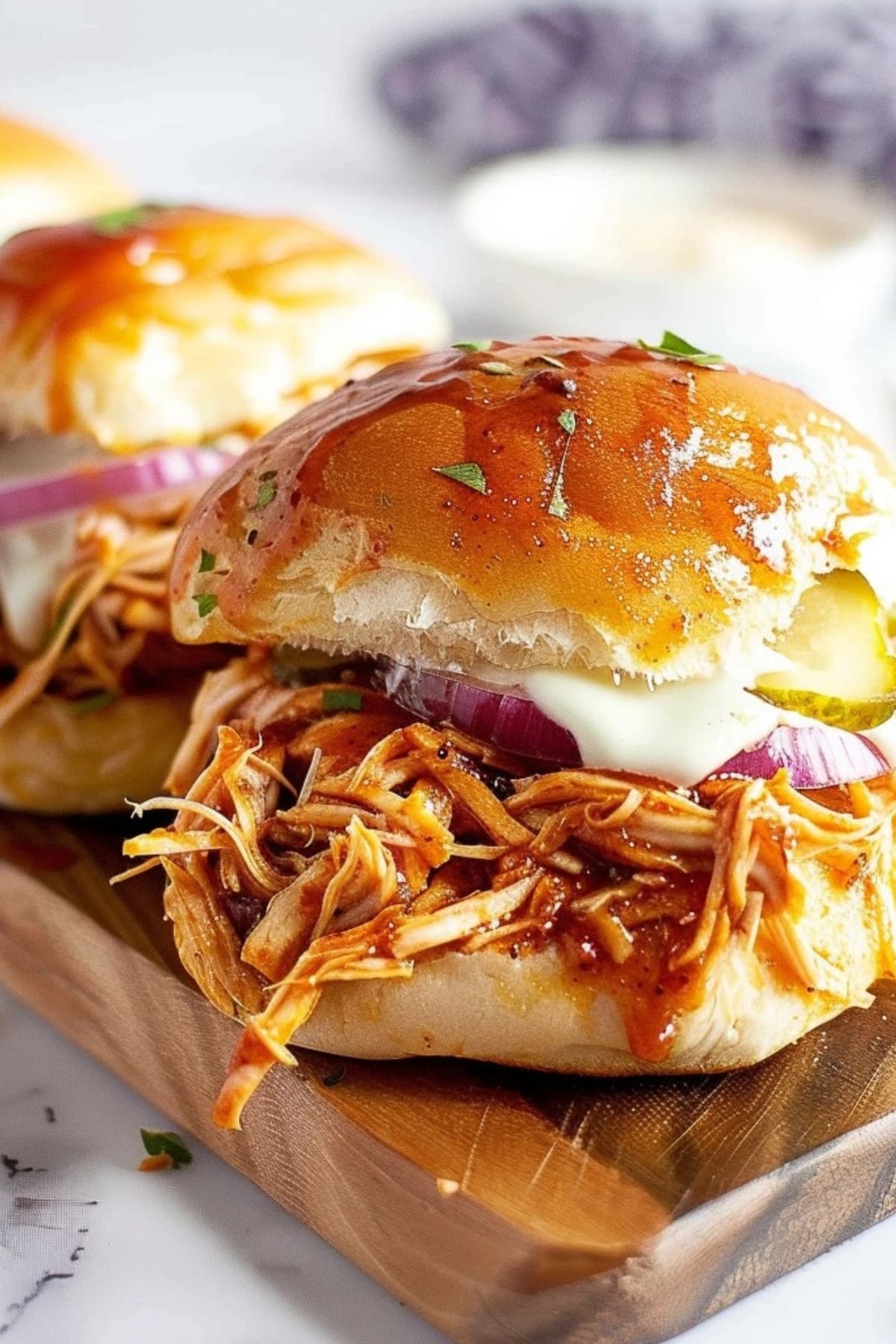 Slider rolls with cheesy BBQ chicken filling with onion and pickles.