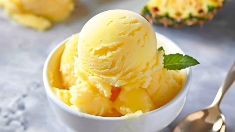 Soft and creamy yellow pineapple sorbet with mint in a bowl