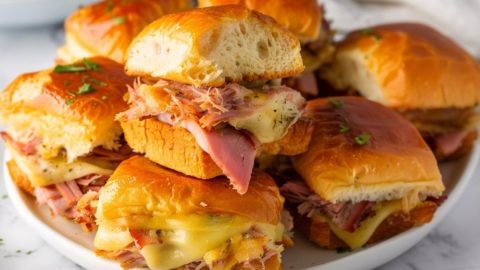 Bunch of pulled apart sliders with cheese stack on a plate.