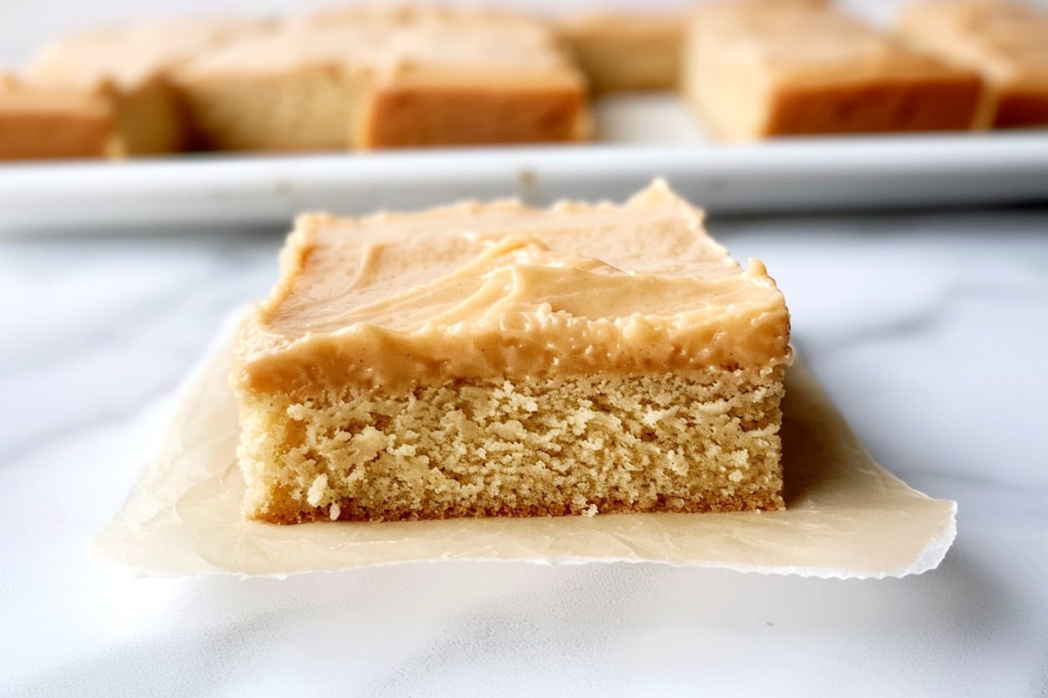 A piece of peanut butter sheet cake square on a parchment paper