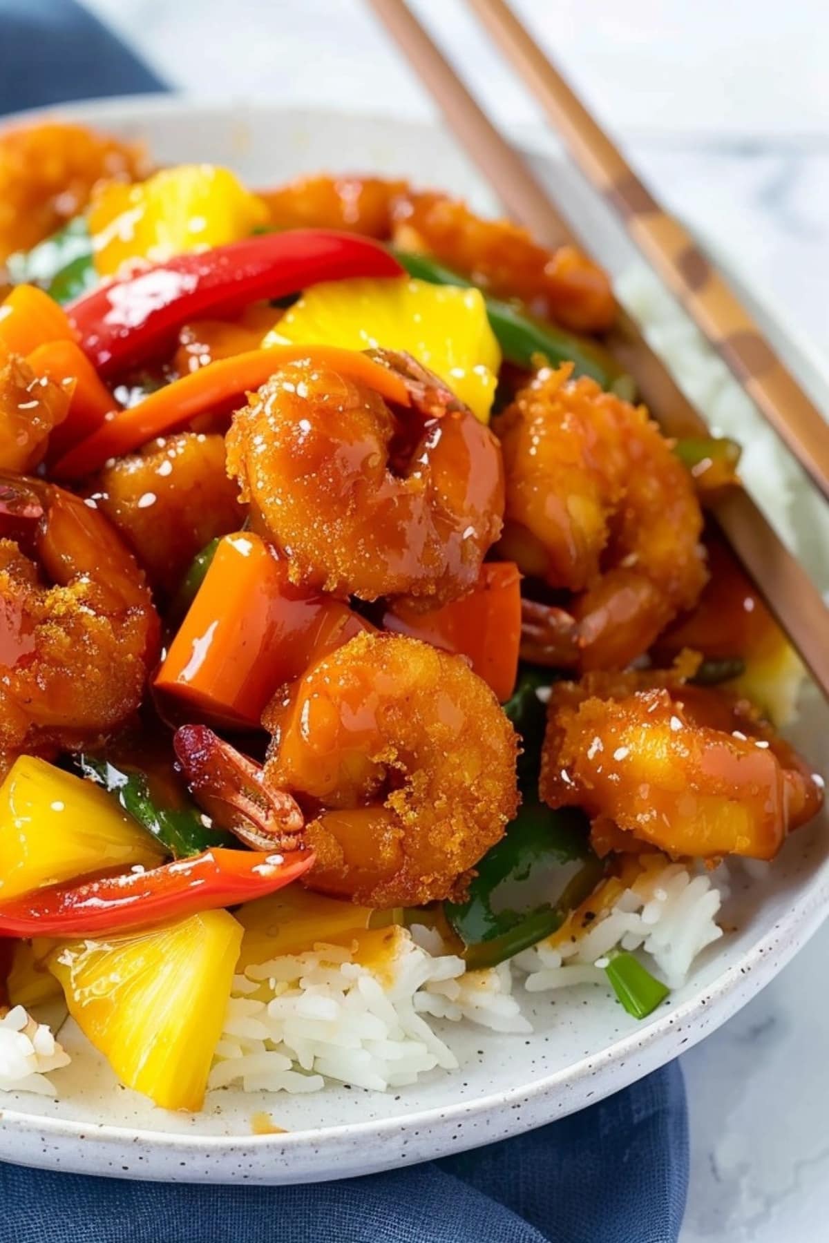 Sweet and sour shrimp with carrots, bell pepper, pineapple chunks served with rice.