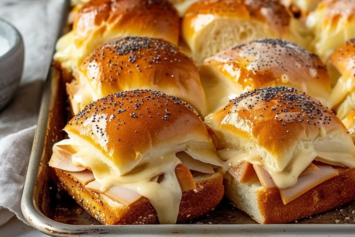 Turkey and cheese sliders on a baking tray.