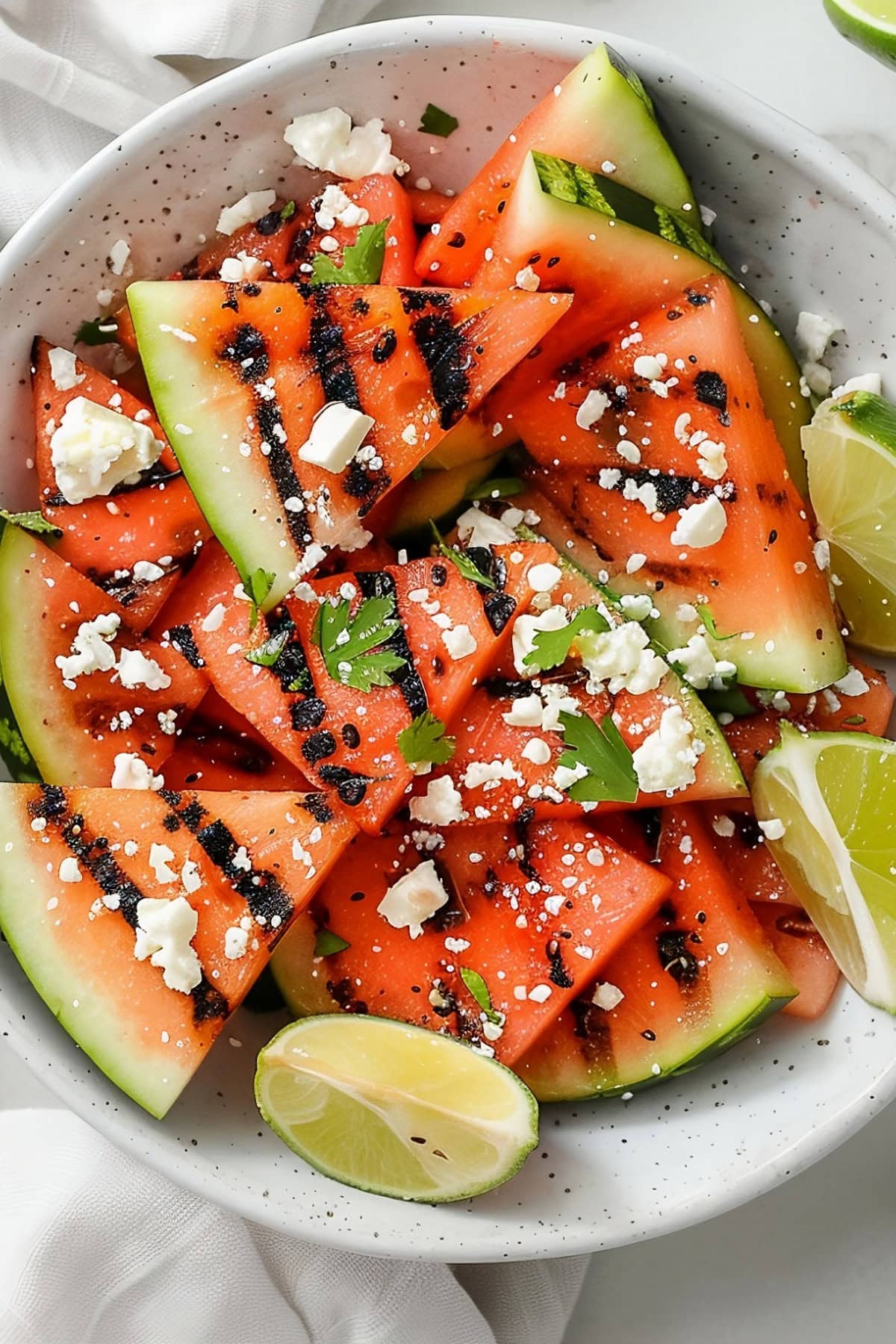 Grilled watermelon appetizer, topped with crumbled feta cheese and herbs