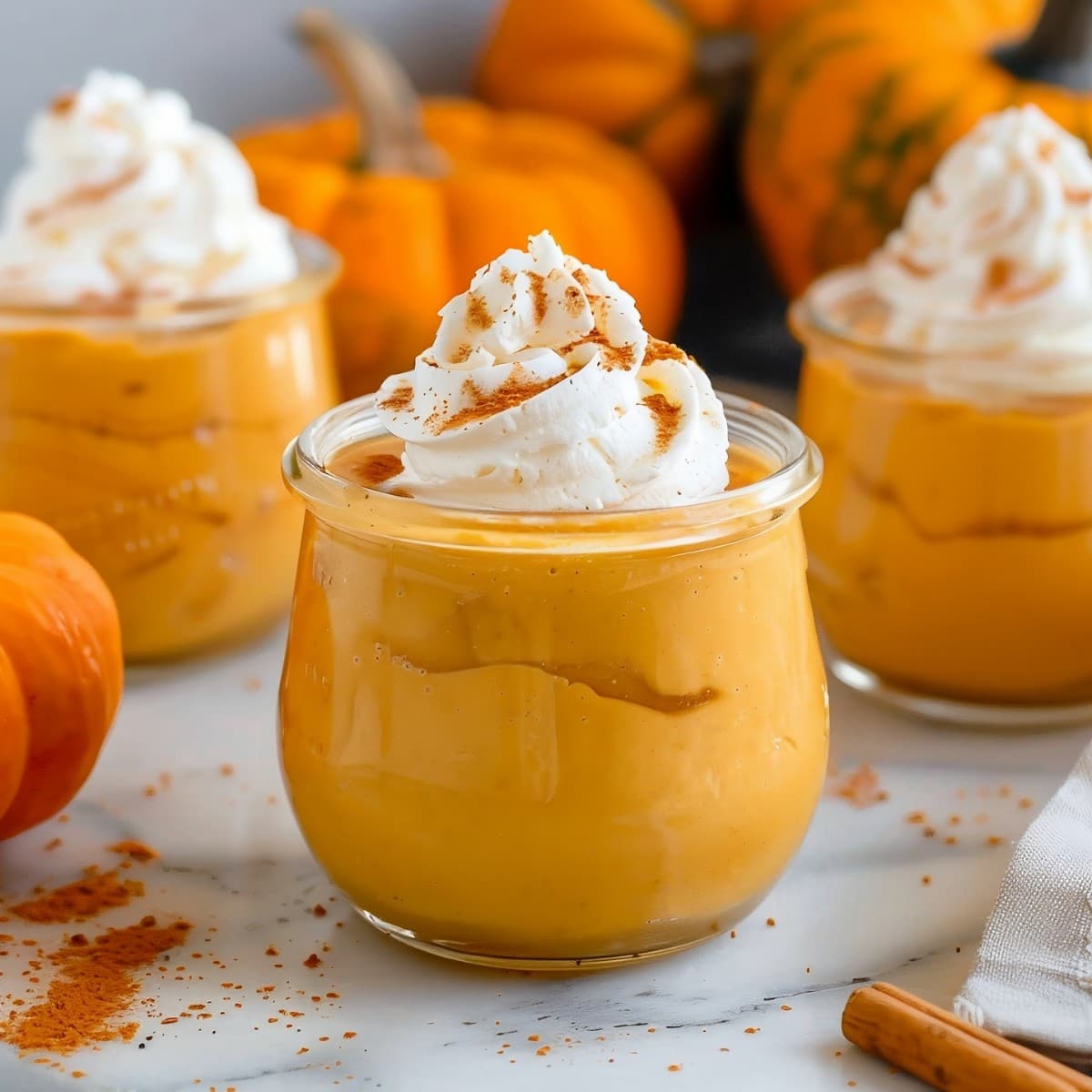 Pumpkin mousse in a glass jar topped with whipped cream and a pinch of cinnamon