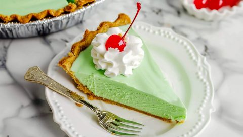 Sliced shamrock shake pie topped with whipped cream and maraschino cherry, a delicious twist on a classic dessert favorite