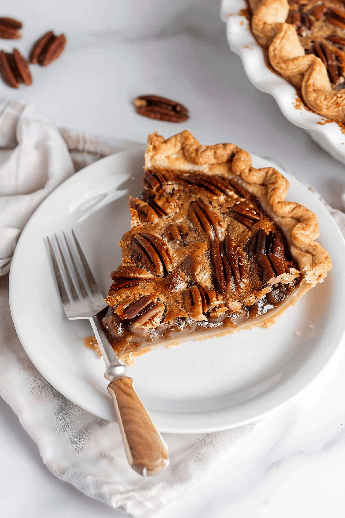 Sliced bourbon pecan pie with flaky and buttery crust in a white plate