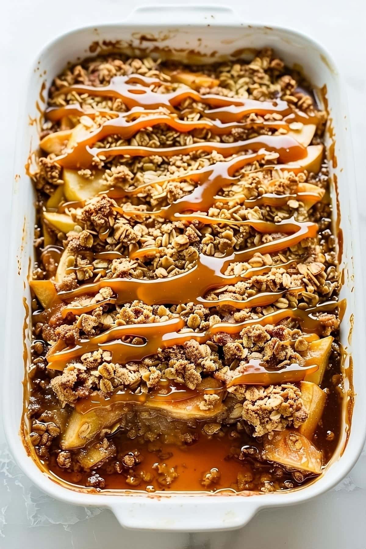 Apple crisp in a baking dish drizzled with caramel sauce, top down view