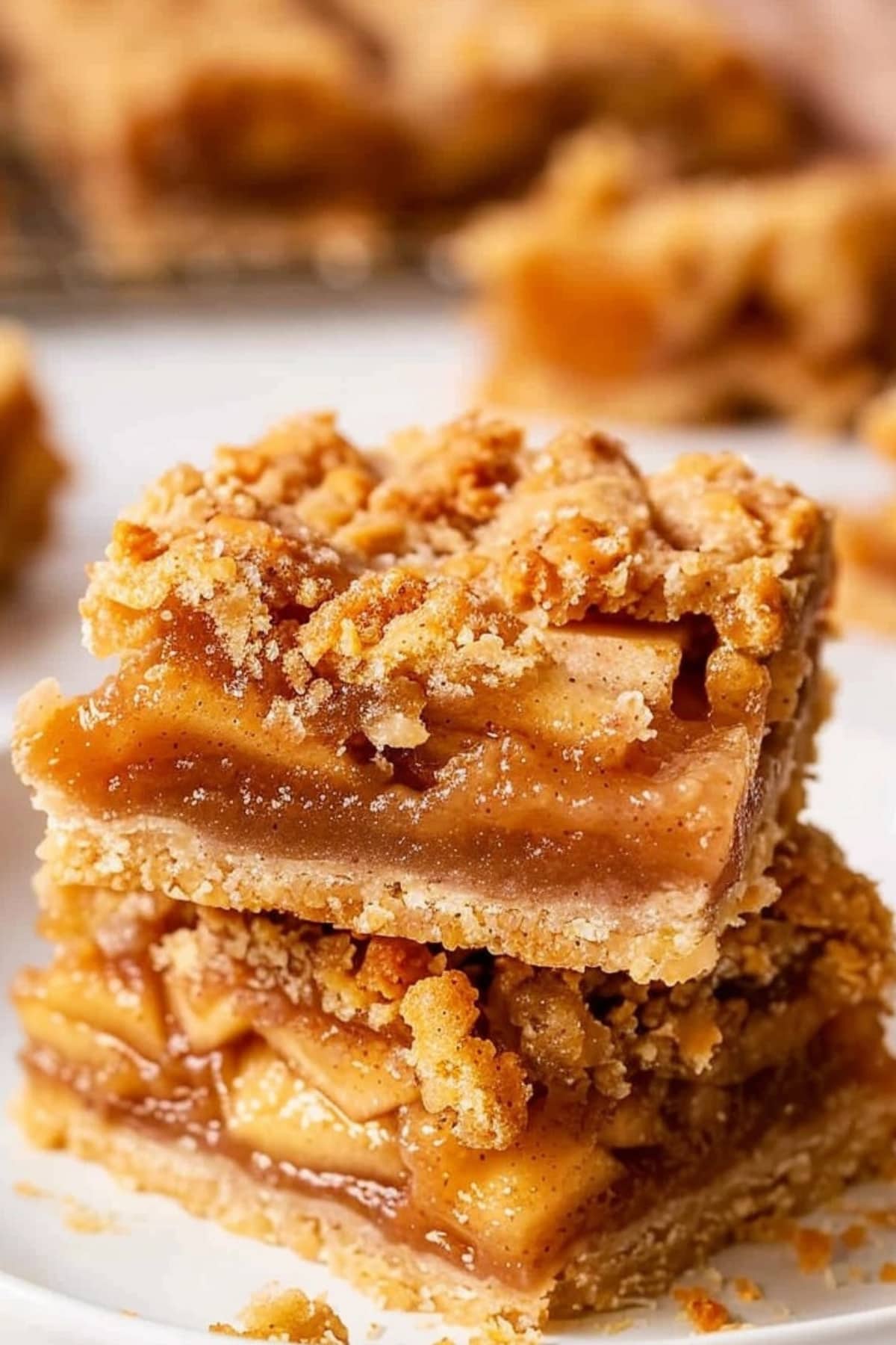 Two slices of apple pie bars stack on each other on a white plate.