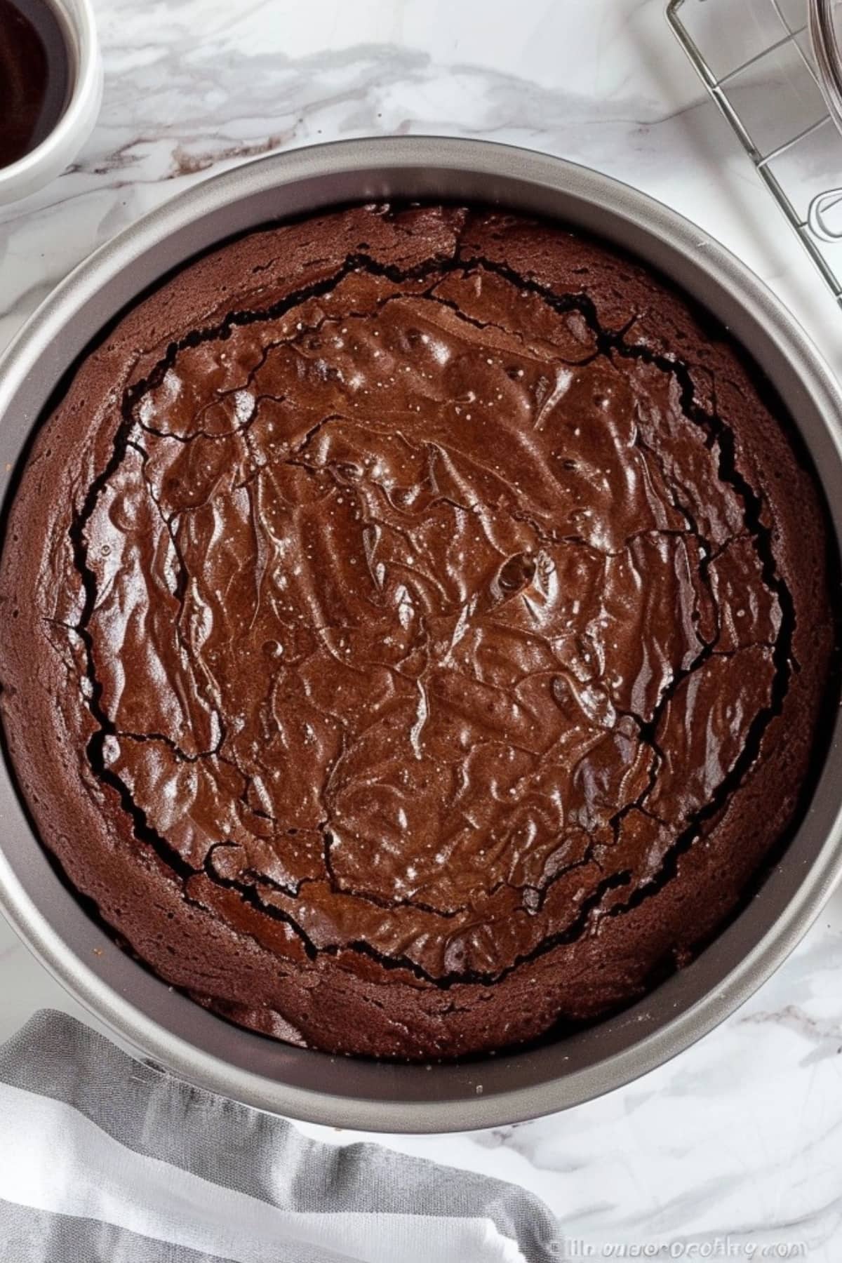 Baked brownie in a 9 inch springform pan sitting on a white marble table, top view.