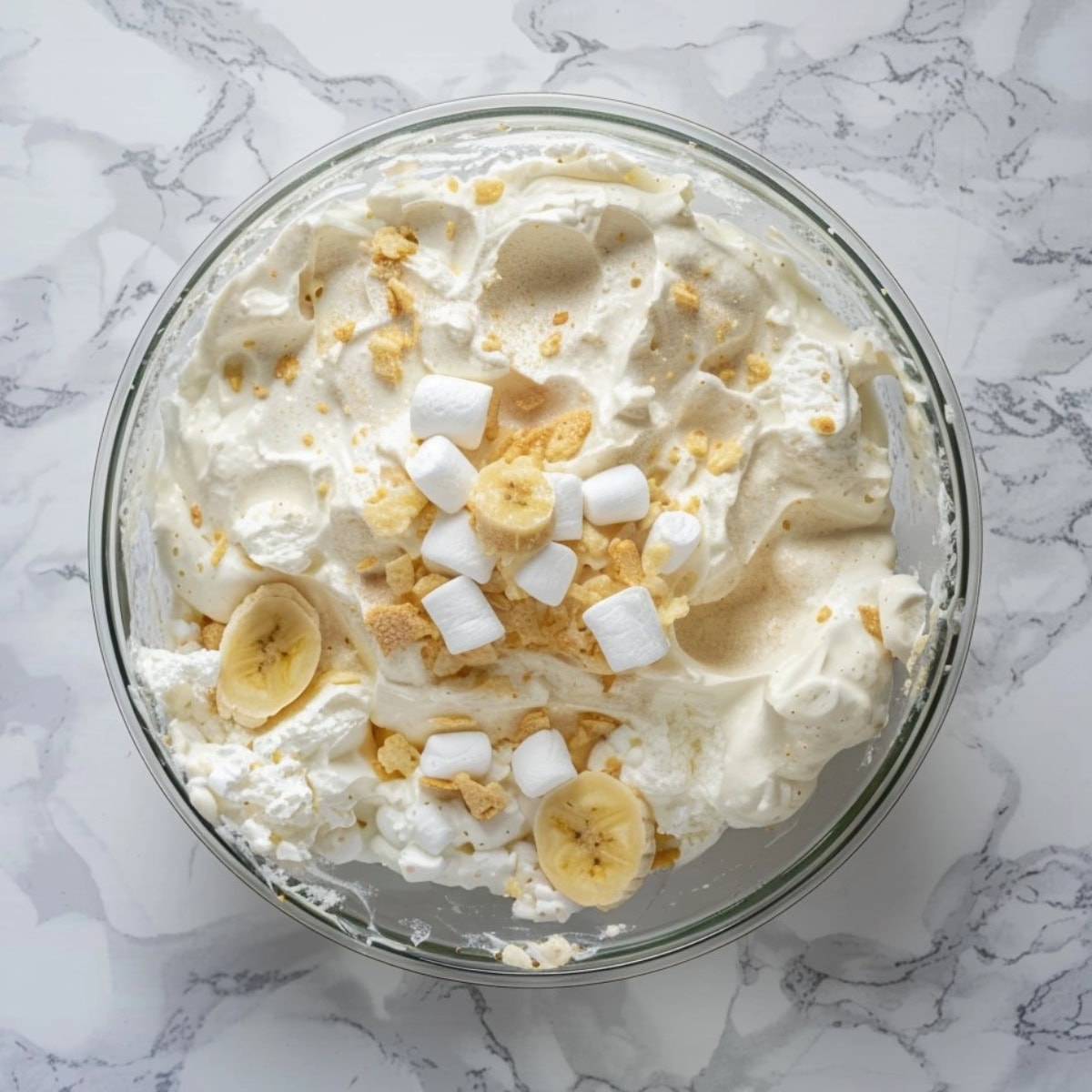 Fluffy pudding with sliced bananas and marshmallows in a glass bowl.