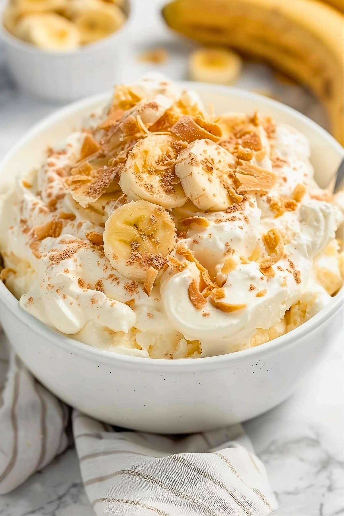 Banana pudding fluff in a bowl with fresh banana slices and crushed Nila wafers on top