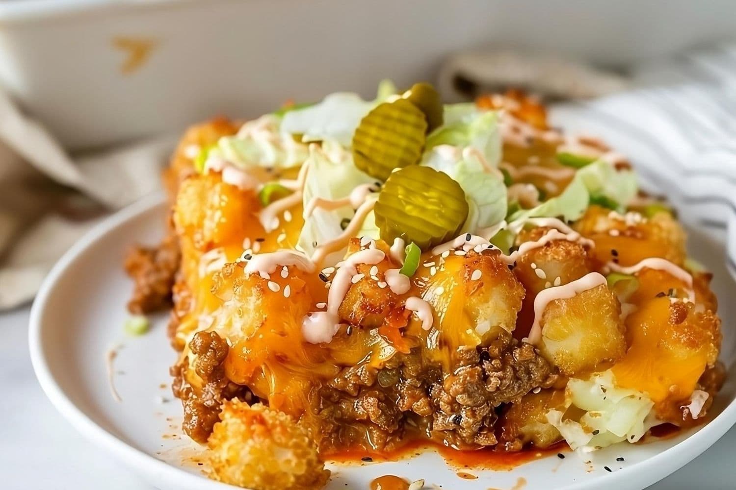 Casserole with tater tots and ground beef in cheesy sauce served in a white plate.
