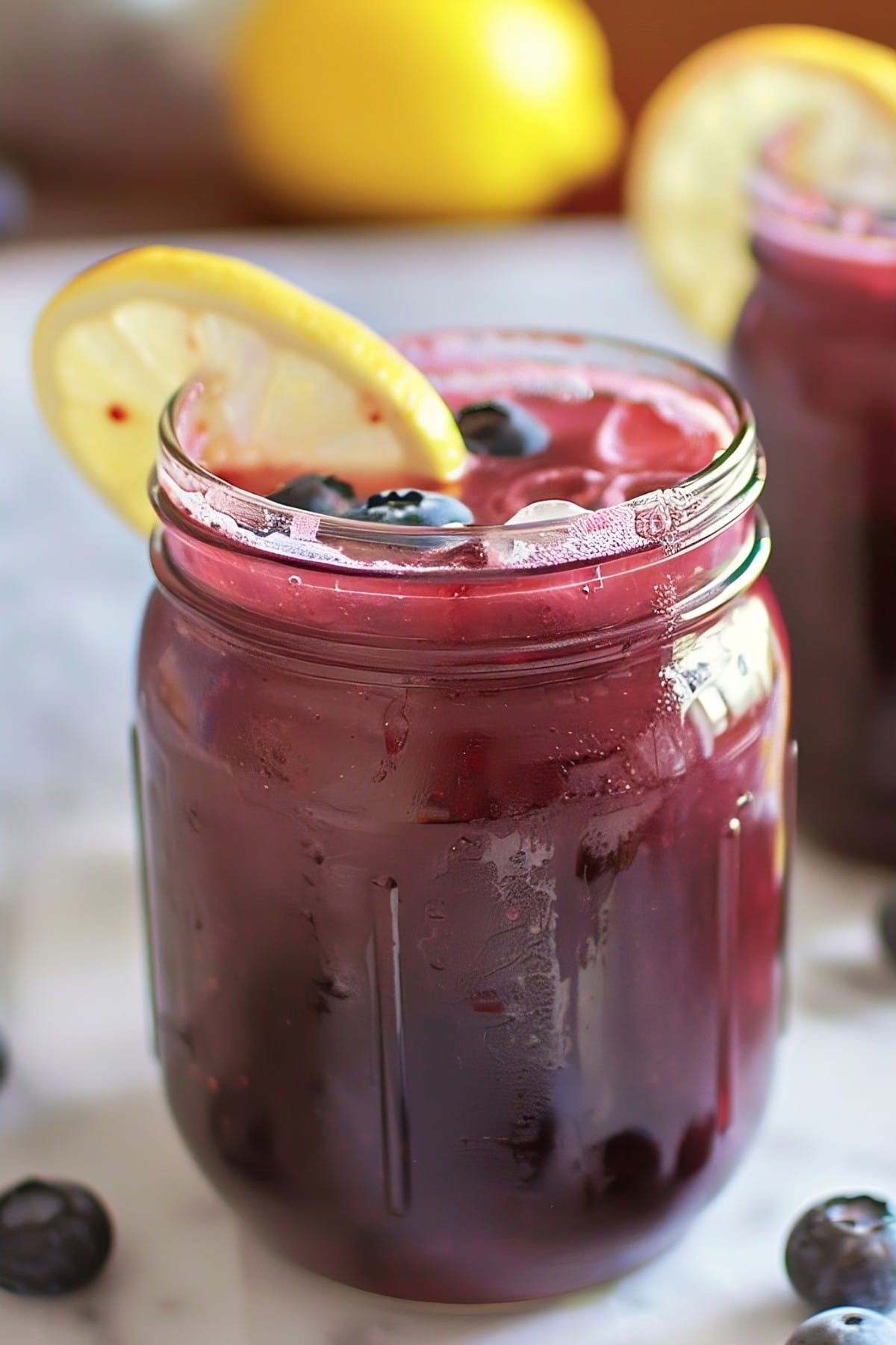 Cold and refreshing homemade blueberry lemonade in mason jars, garnished with lemon