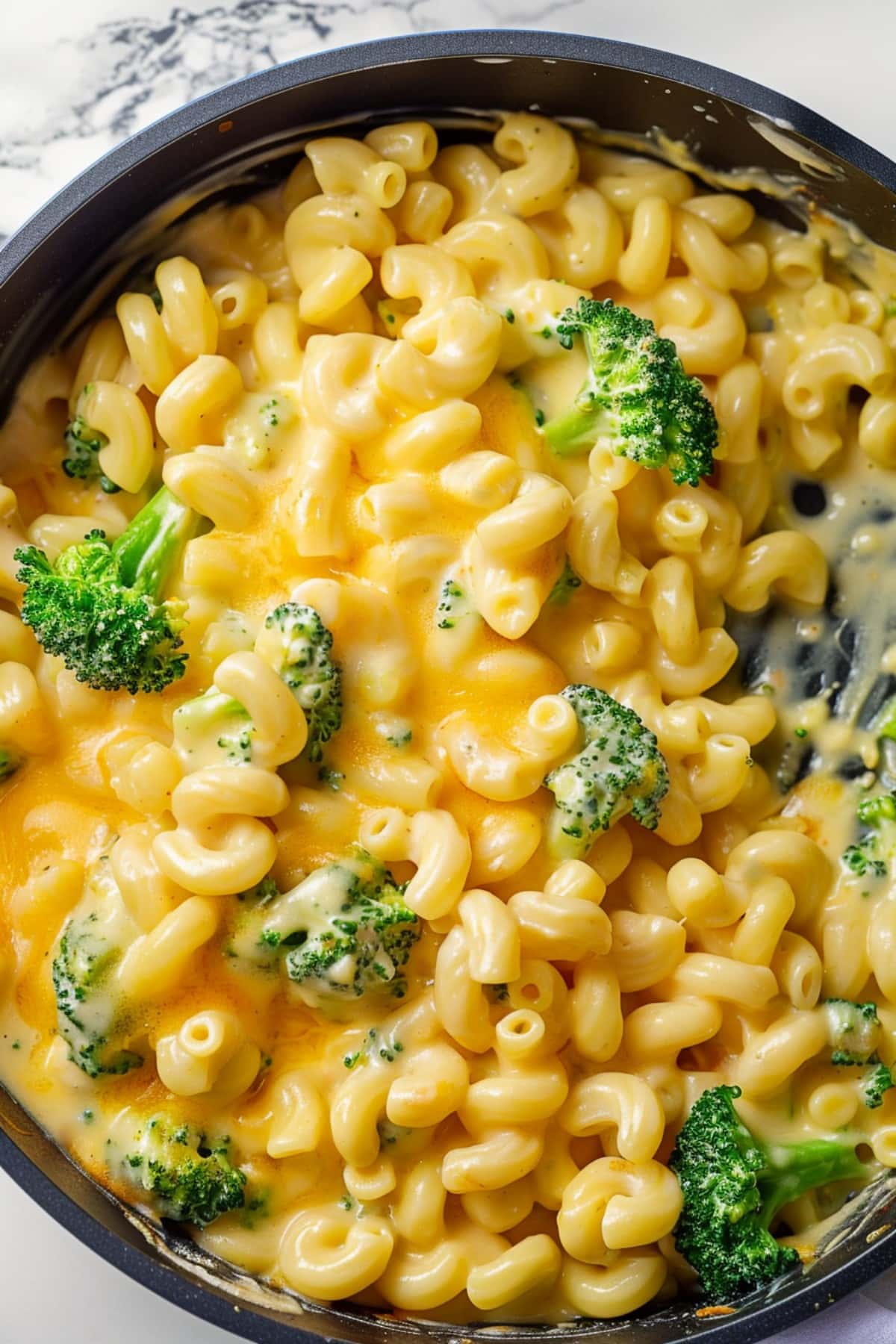 Cheesy and hearty homemade broccoli cheddar mac and cheese in a skillet, overhead view