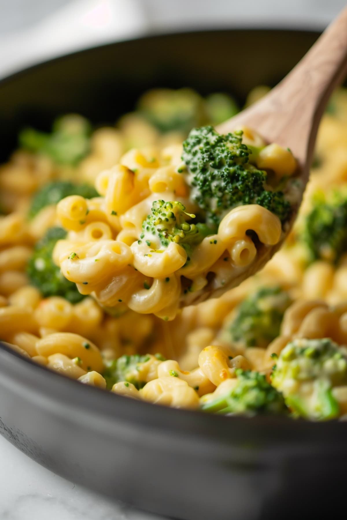 Cheesy mac and cheese with broccoli in a wooden spoon