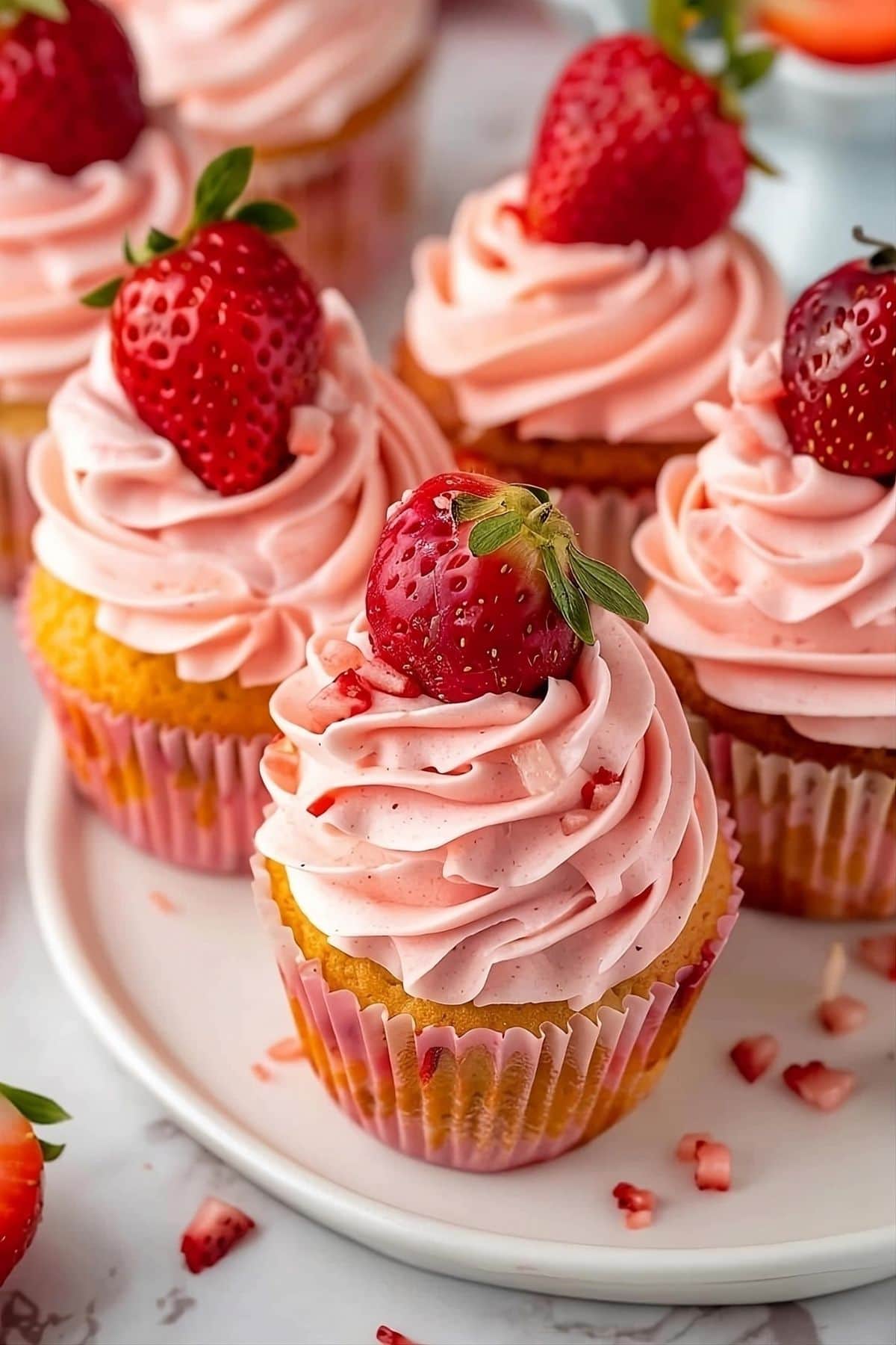 Strawberry cupcakes with strawberry buttercream frosting served in a white plate.