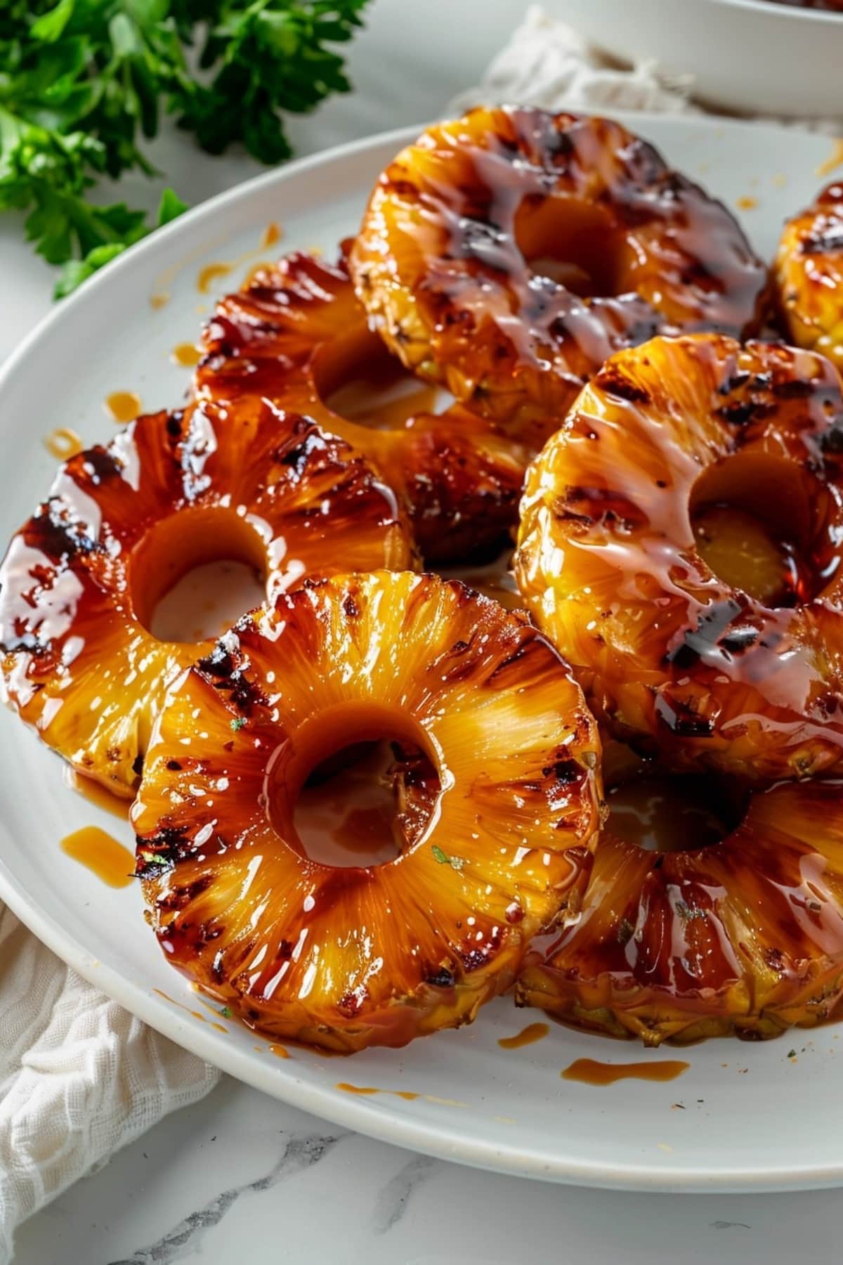Grilled pineapple rings with sugary glaze served on a white plate.