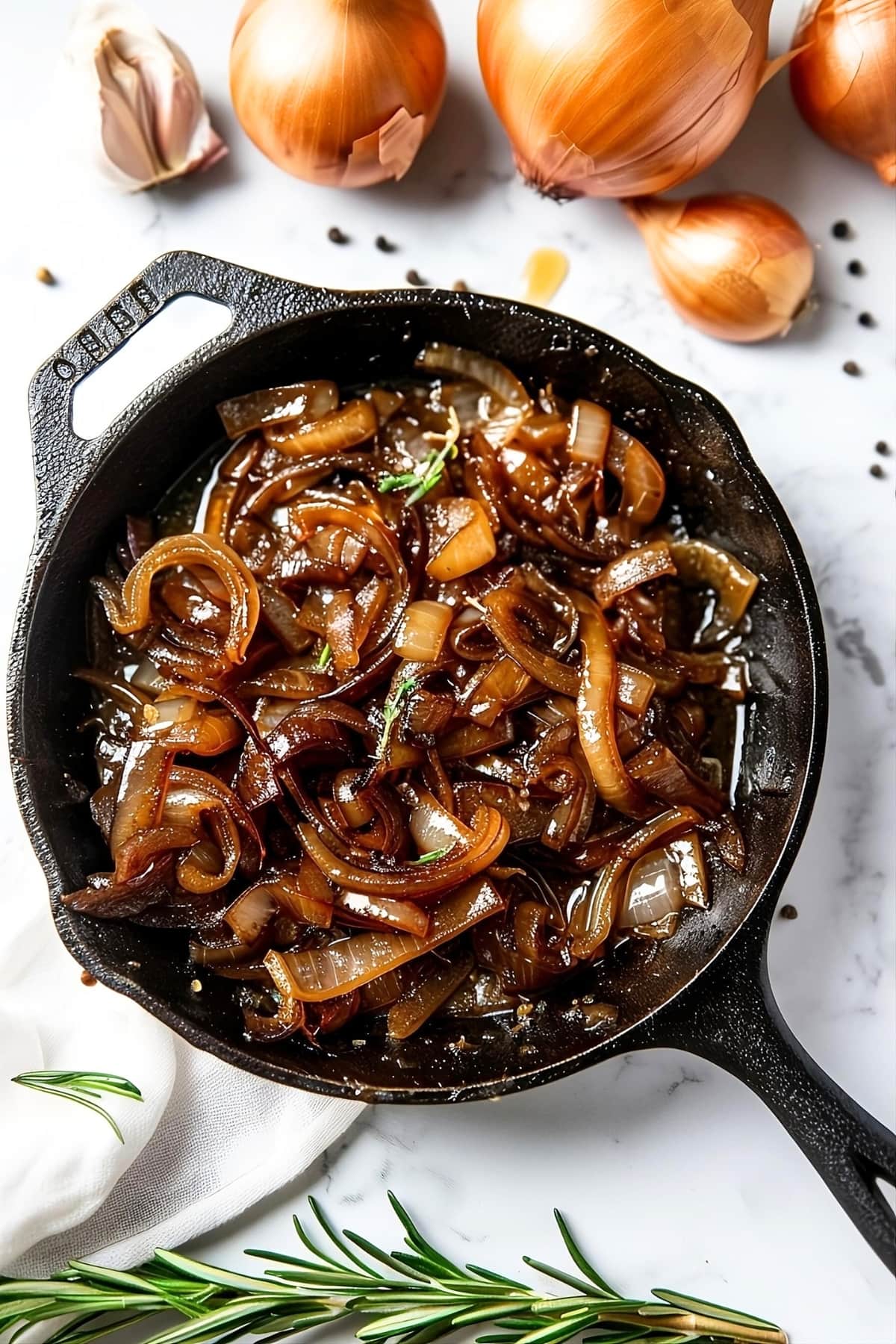 Caramelized onion in a cast iron skillet on a white marble surface.
