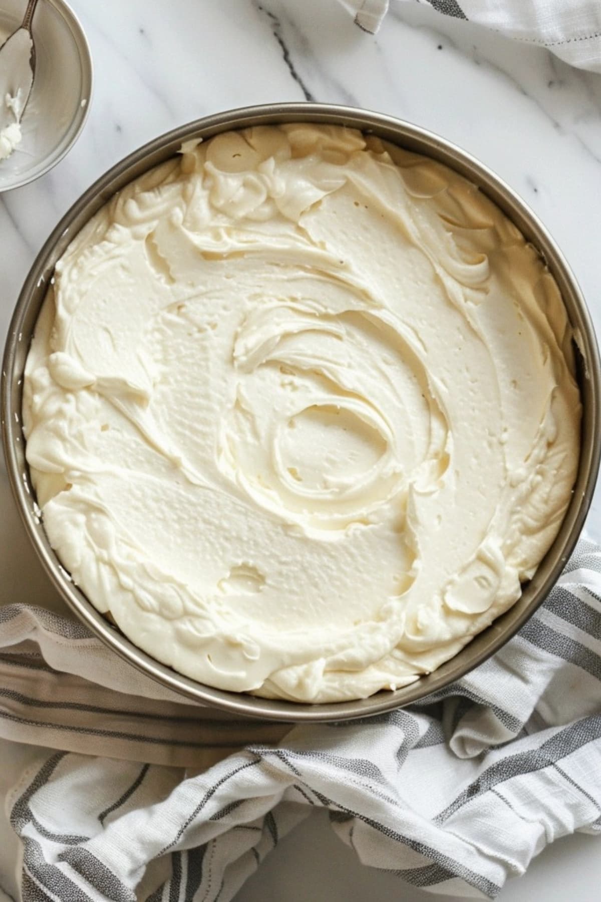 Cheesecake prepared in round springform pan sitting on a white marble table.