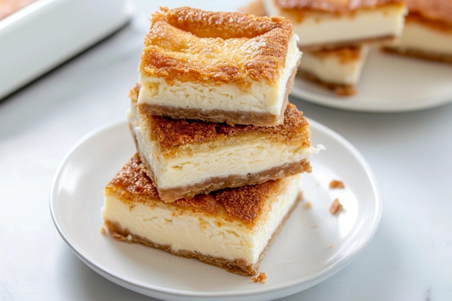 Stack of square slices of cheesecake crescent rolls in a white plate.