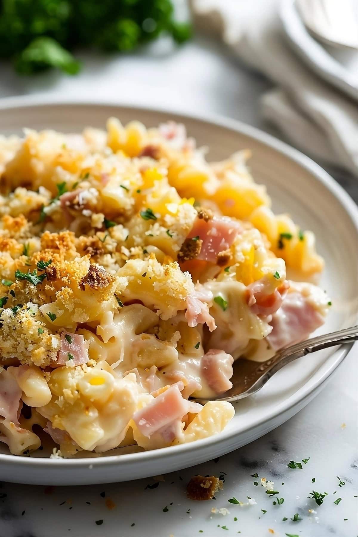 Cheesy ham and noodle casserole served on a plate.