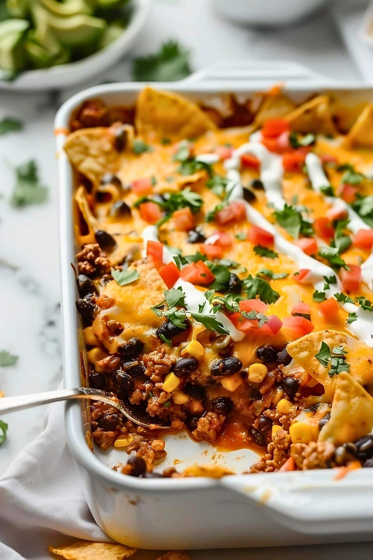 Taco casserole with sour cream drizzle and cheesy toppings.