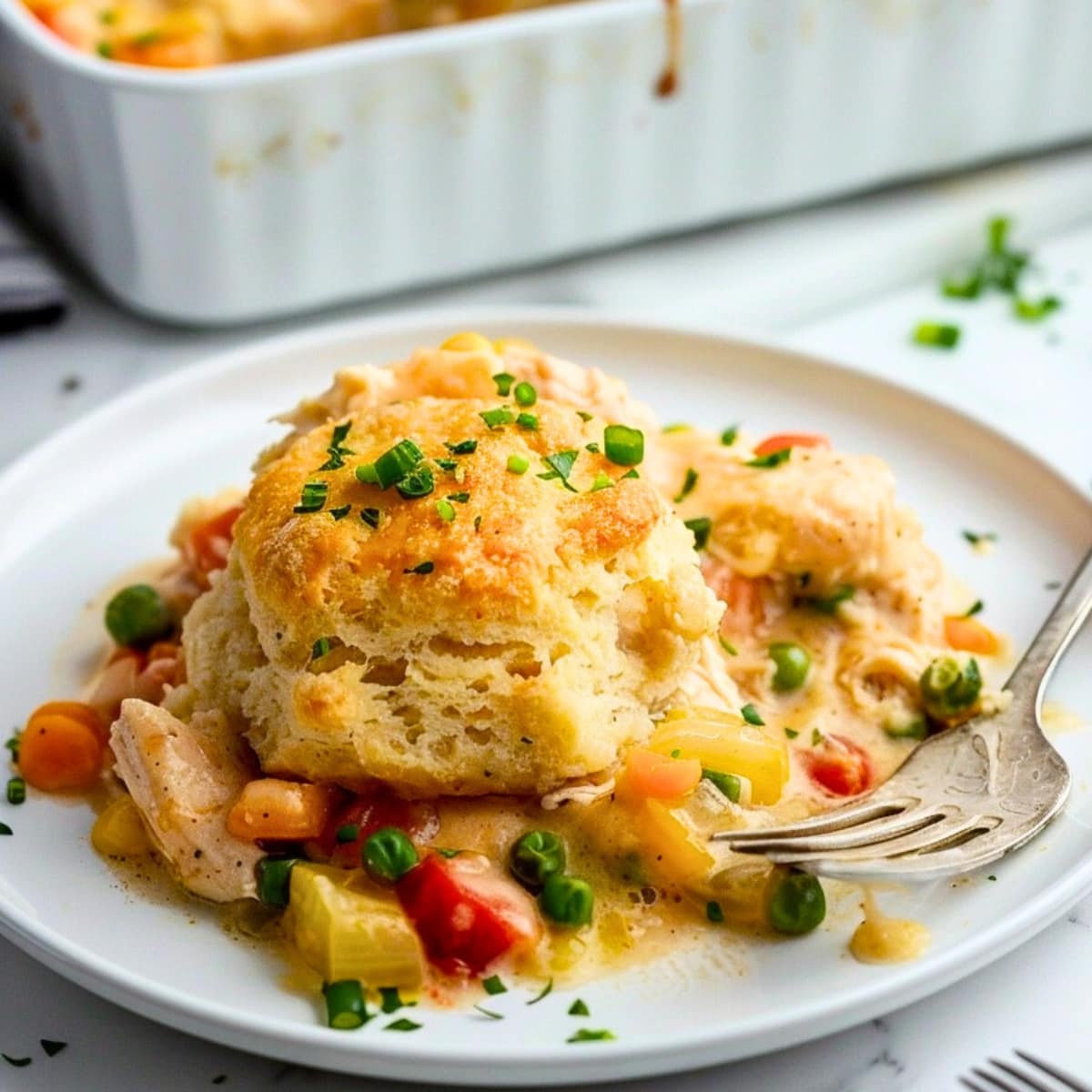 Serving of chicken and biscuit casserole in a white plate with fork.