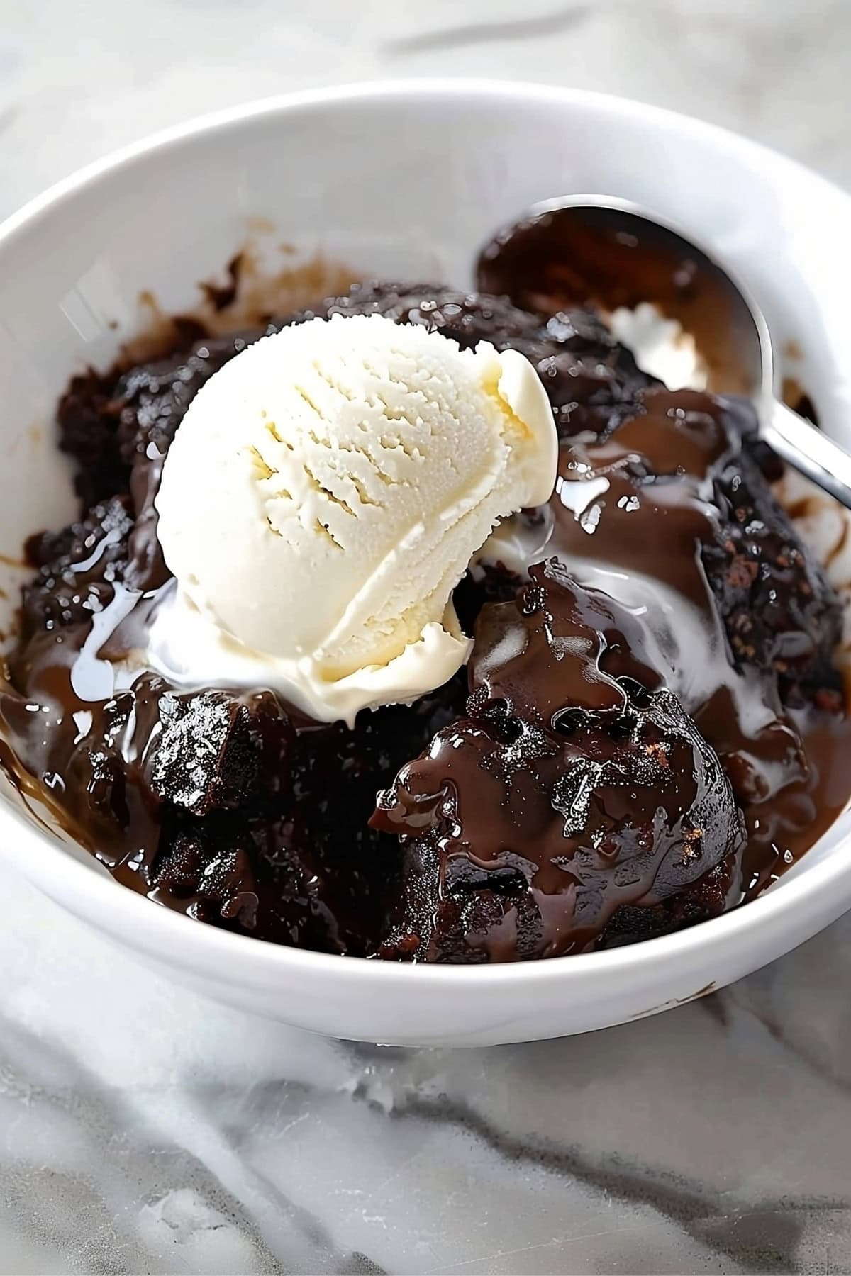 A serving of gooey and moist chocolate cobbler served in a white bowl.
