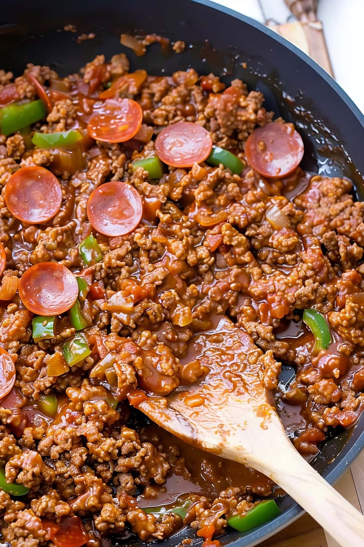 A skillet filled with saucy ground beef, peppers and onions