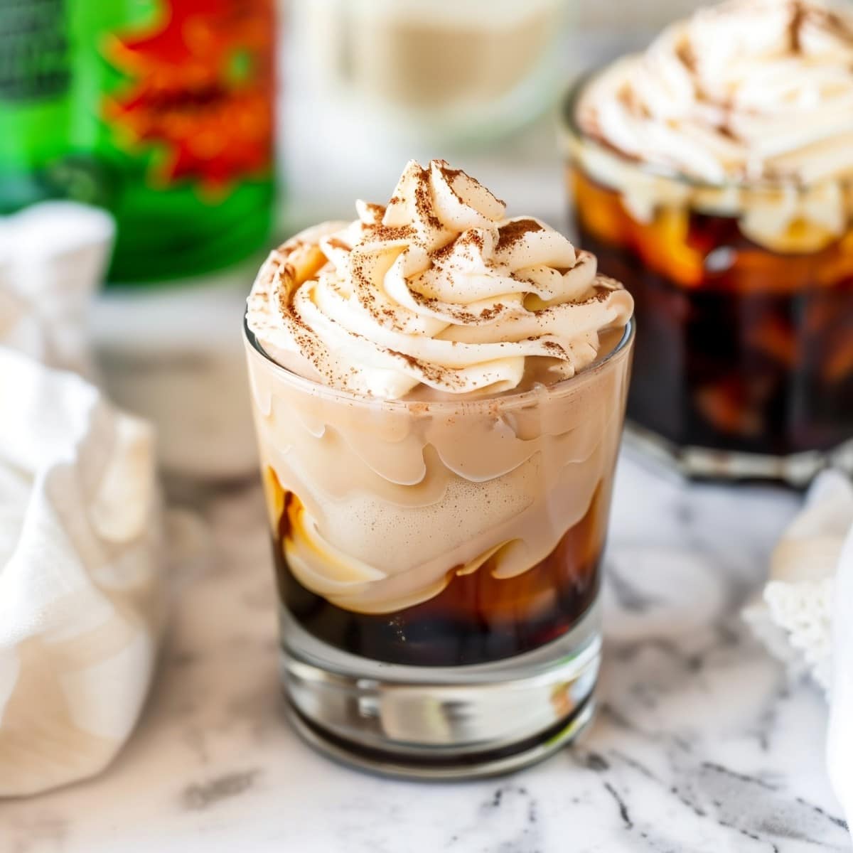 A shot glass of coffee liqueur topped with Kahlua whipped cream