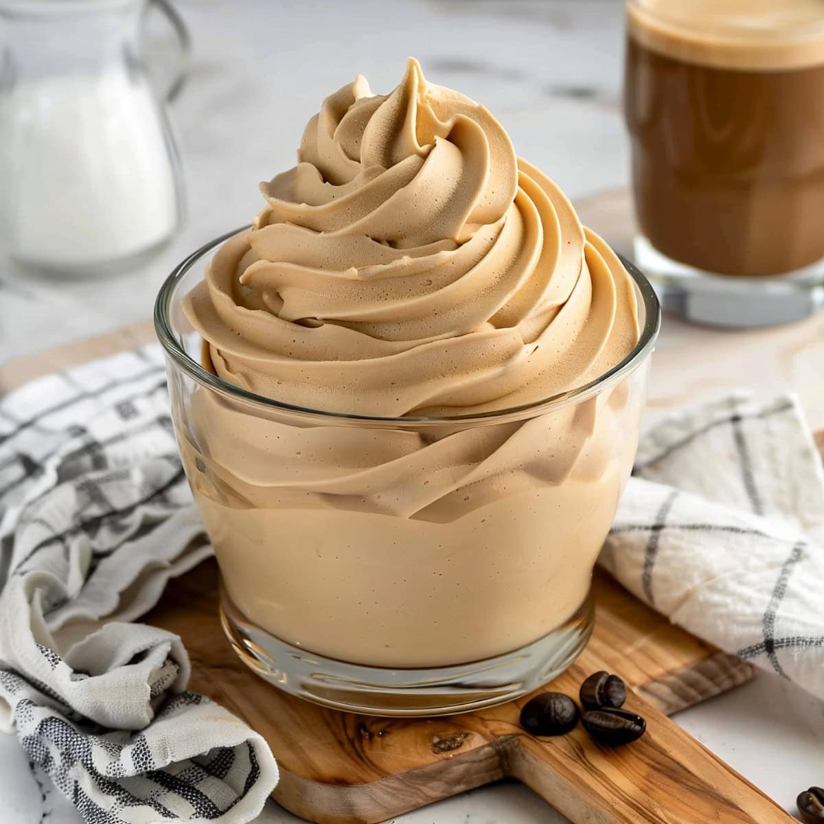 Soft and fluffy coffee whipped cream in a glass bowl, sitting in a wooden board