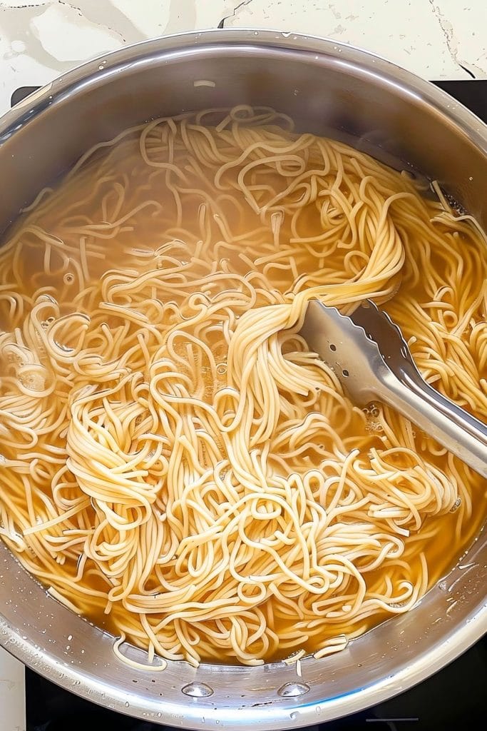 A pan filled with noodles cooked in a stove