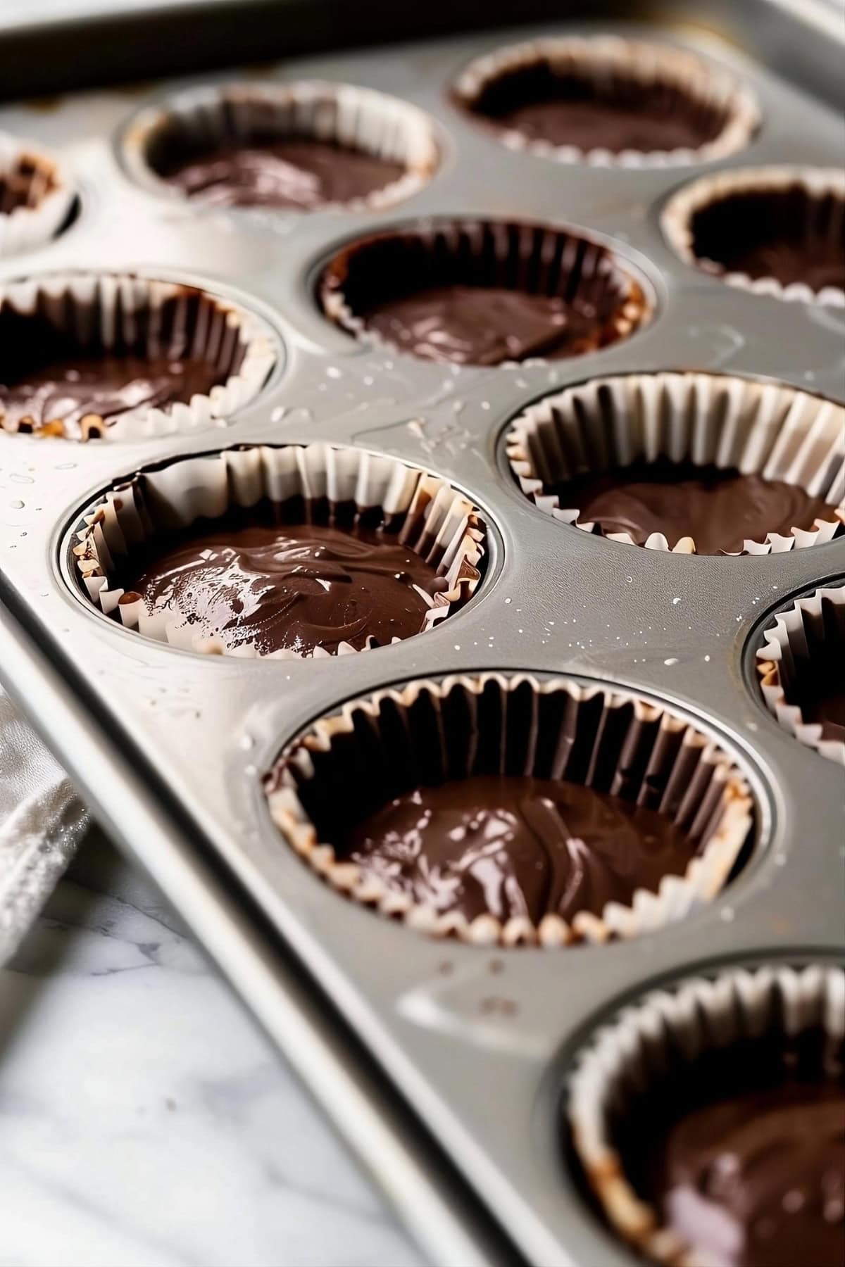 Cupcakes with chocolate mixture in a cupcake tray.