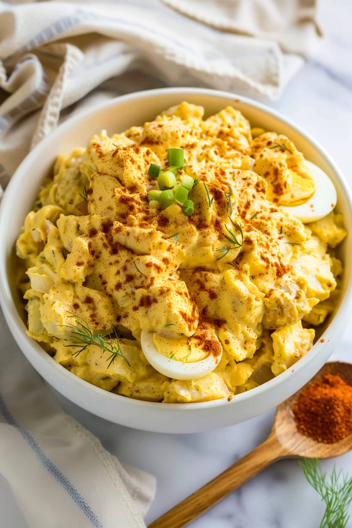 Flavorful potato salad with a deviled egg twist, topped with chopped green onions and dill, perfect for picnics and potlucks