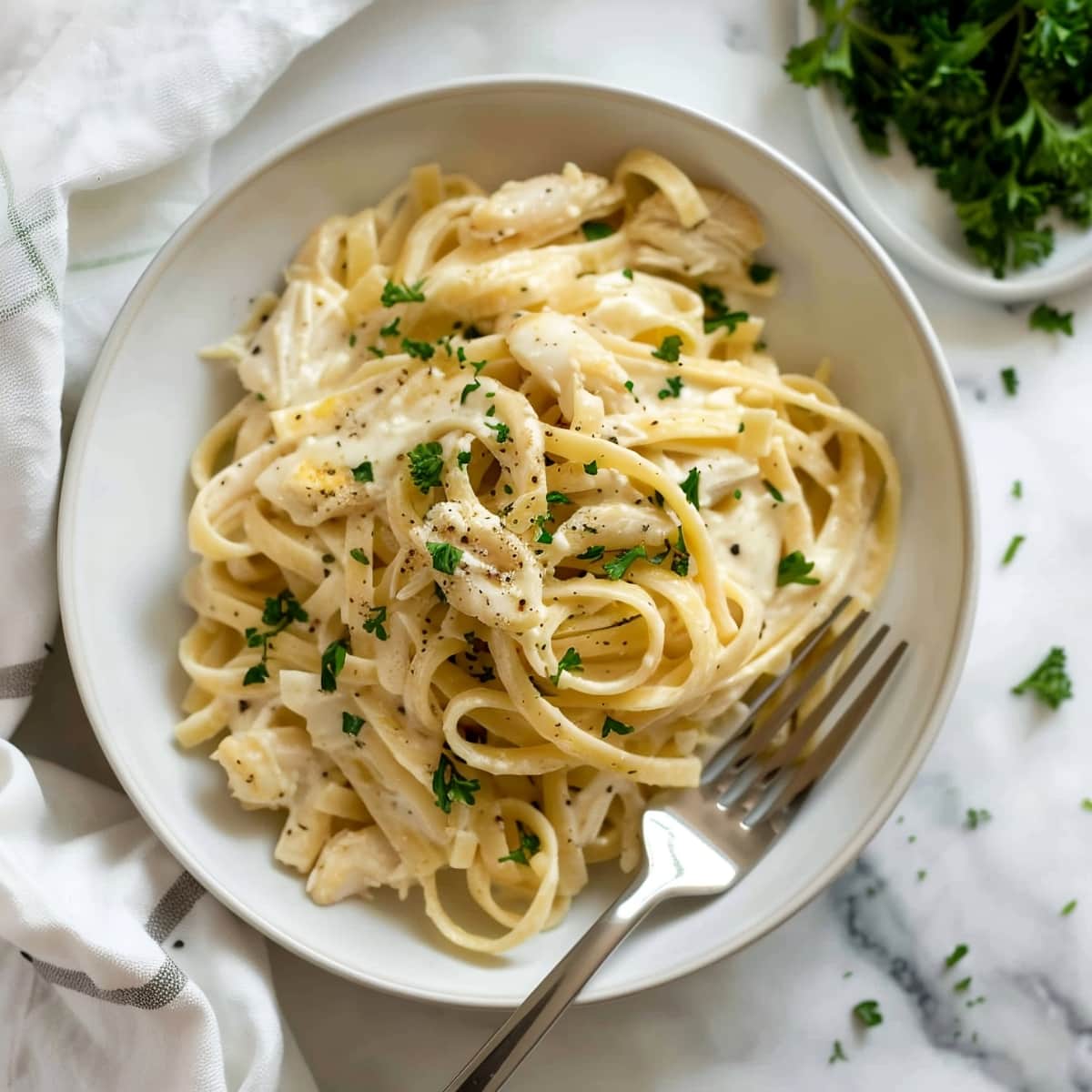 Creamy and delicious homemade crab fettucine alfredo in a white bowl with fork