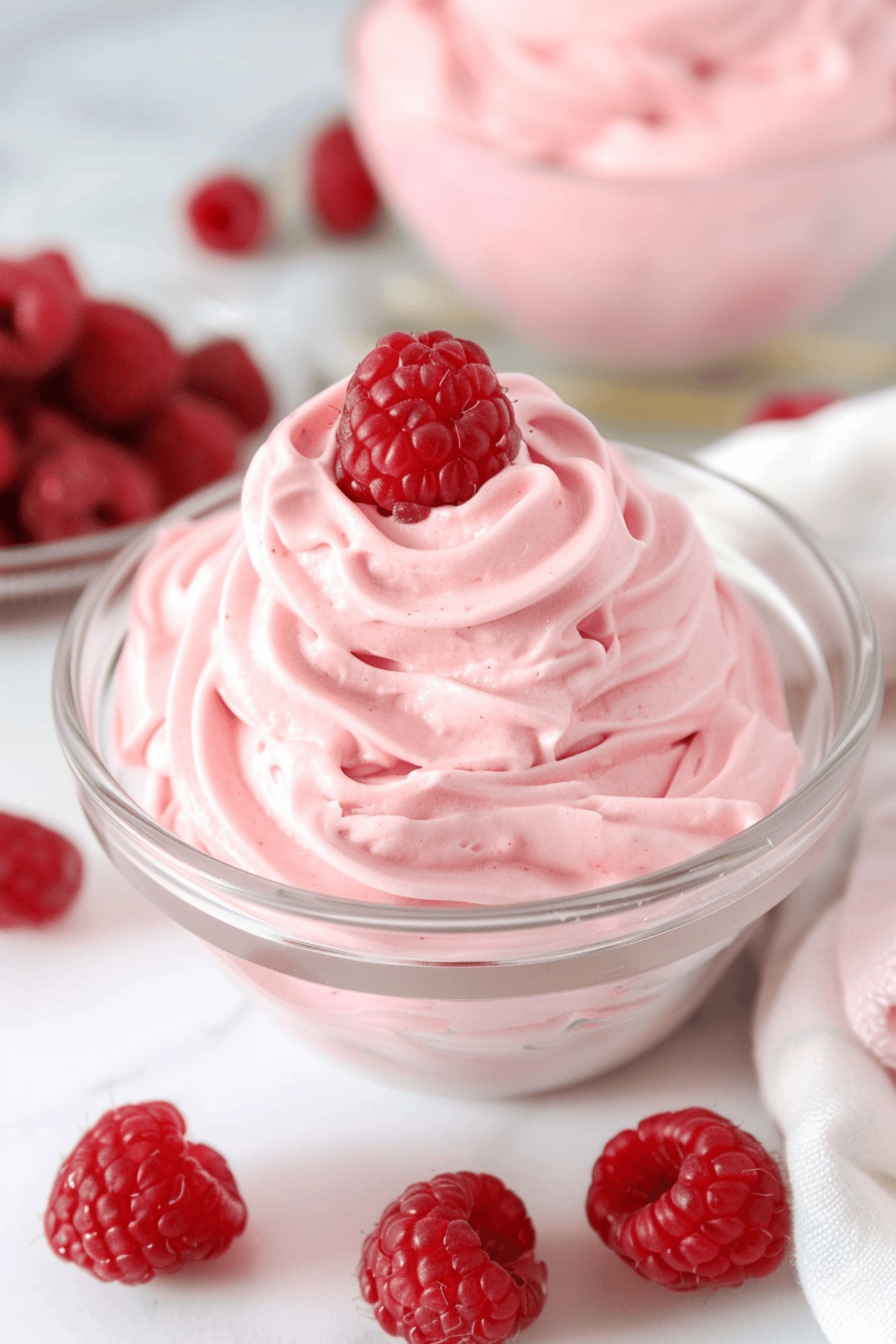 Swirls of raspberry whipped cream in a glass bowl woth fresh berries