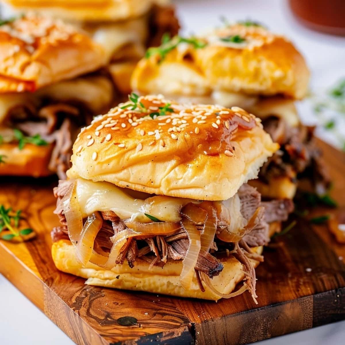 French dip sliders with roast beef and caramelized onions on a wooden board
