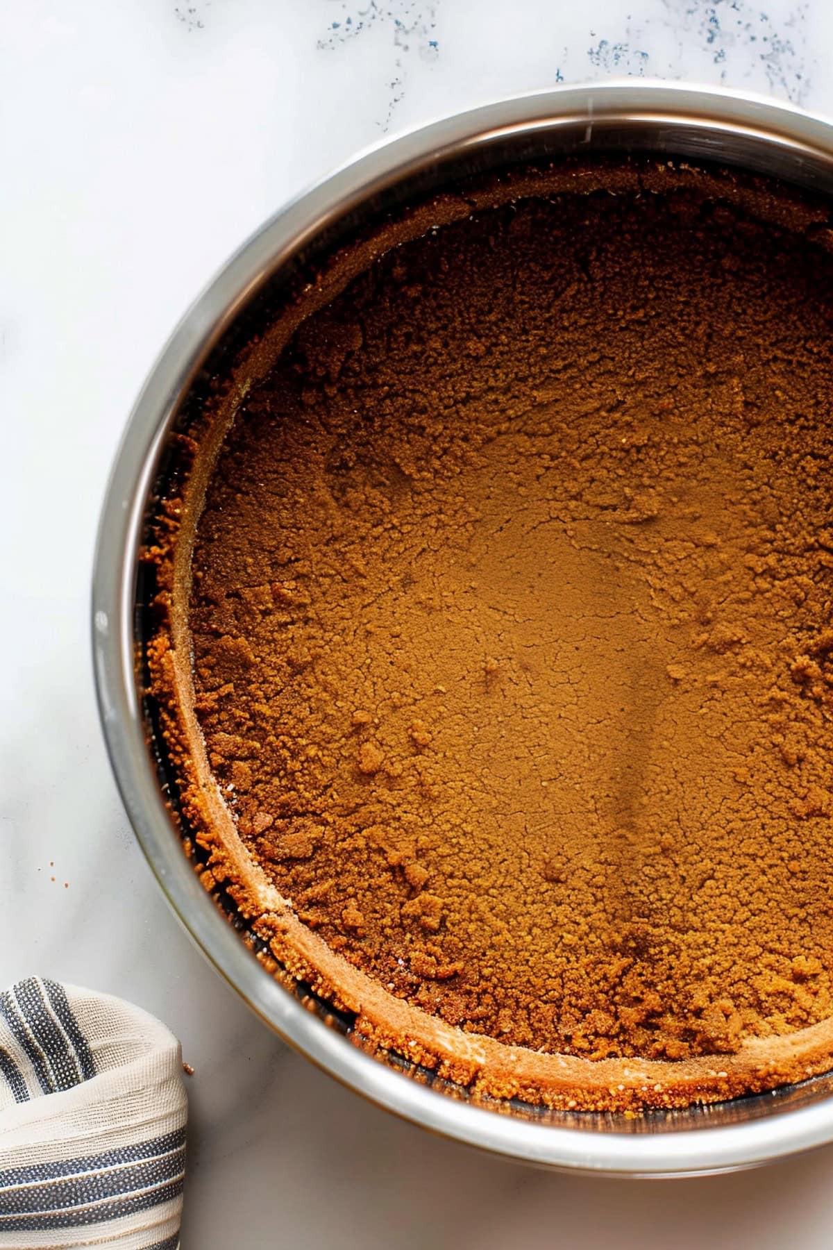 Overhead view of gingersnap cookie crumb crust in a stainless container