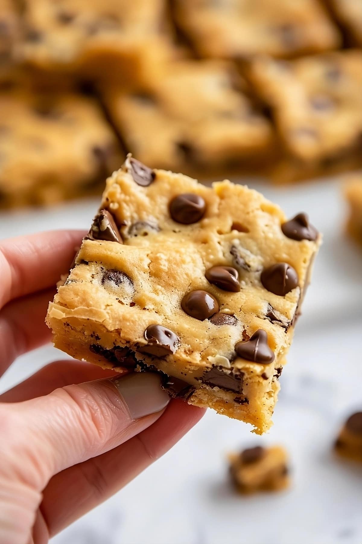 Hand holding cake mix cookie bars with chocolate chips.