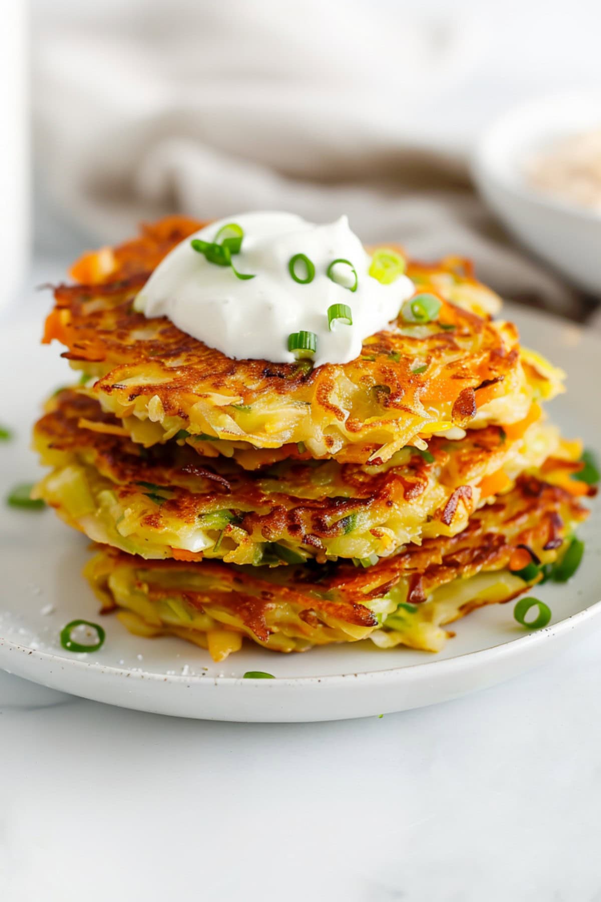 Crispy cabbage fritters with carrots and scallions, topped with sour cream