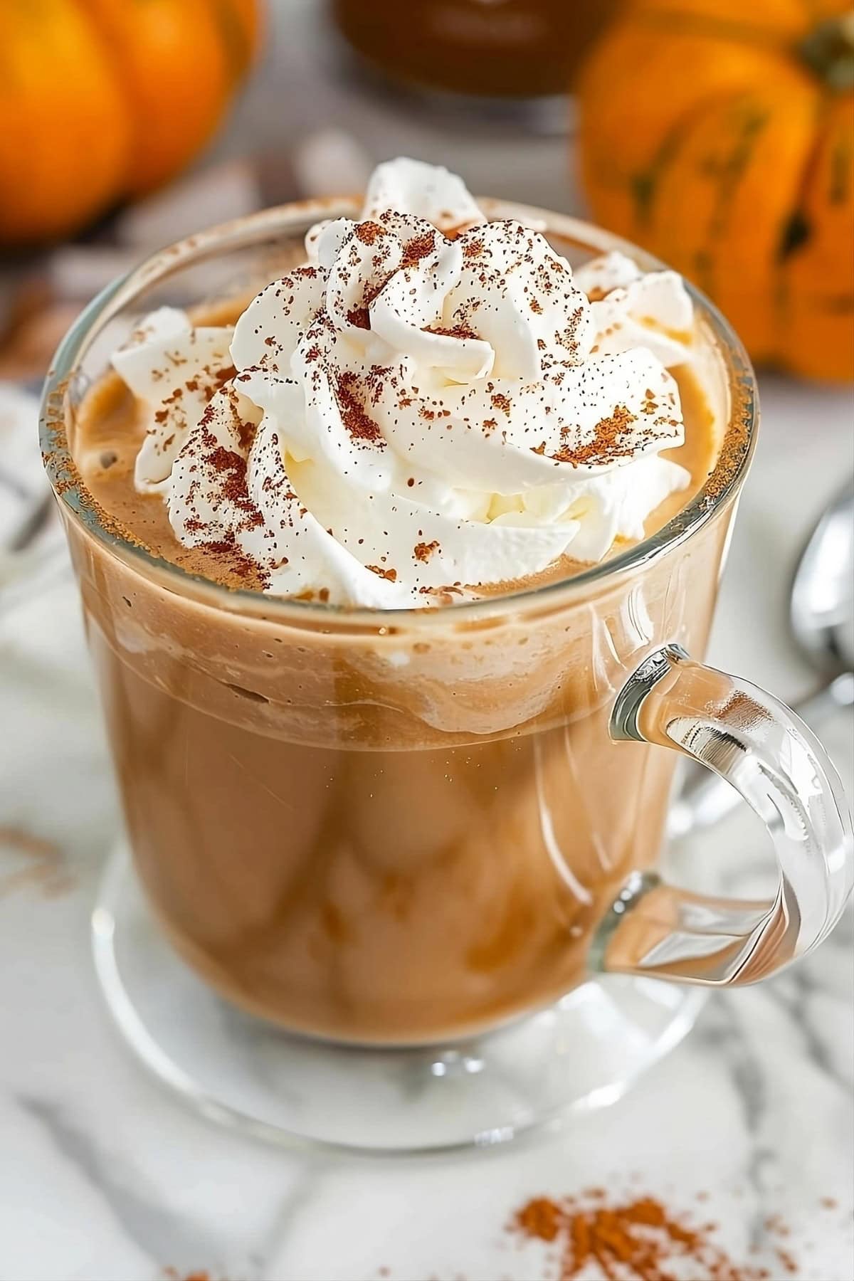 Hot chocolate with pumpkin spices in a glass mug with whipped cream.