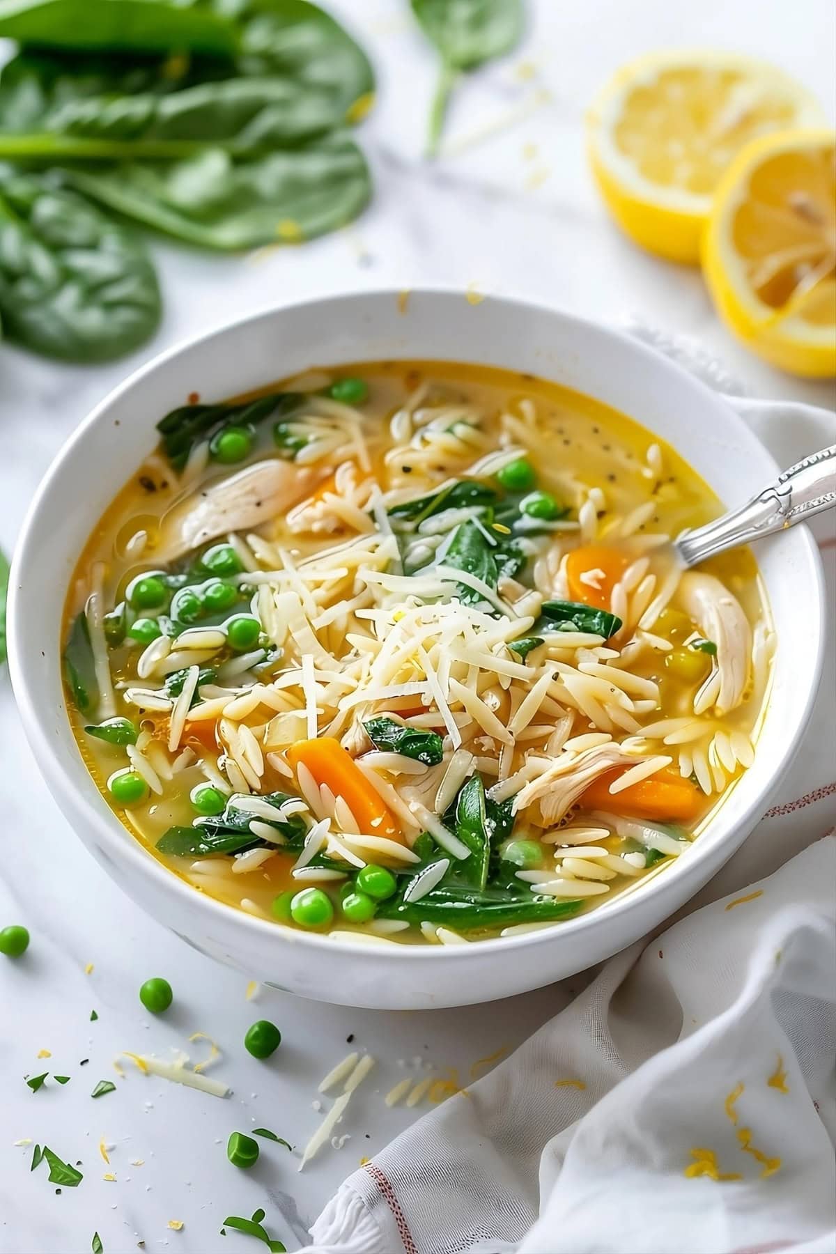 Lemon chicken orzo soup garnished with parmesan cheese served in a white bowl.
