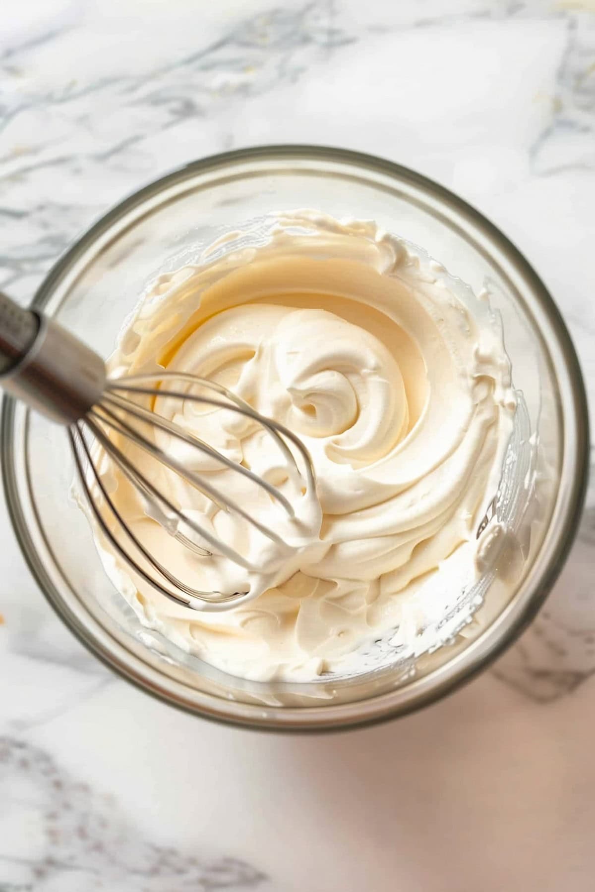 A glass bowl of mixed ingredients for peanut butter whipped cream