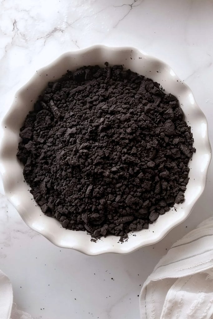Overhead view of Oreo crumbs in a ceramic pie dish