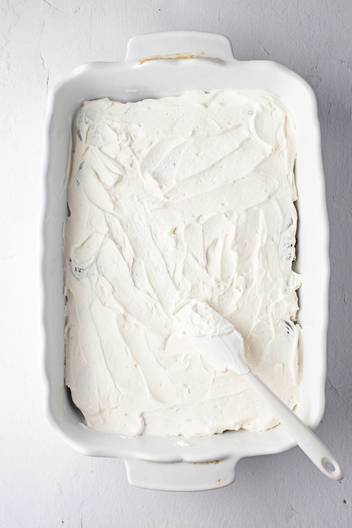 Layered heavy whipping cream with oreo cookies in a baking dish