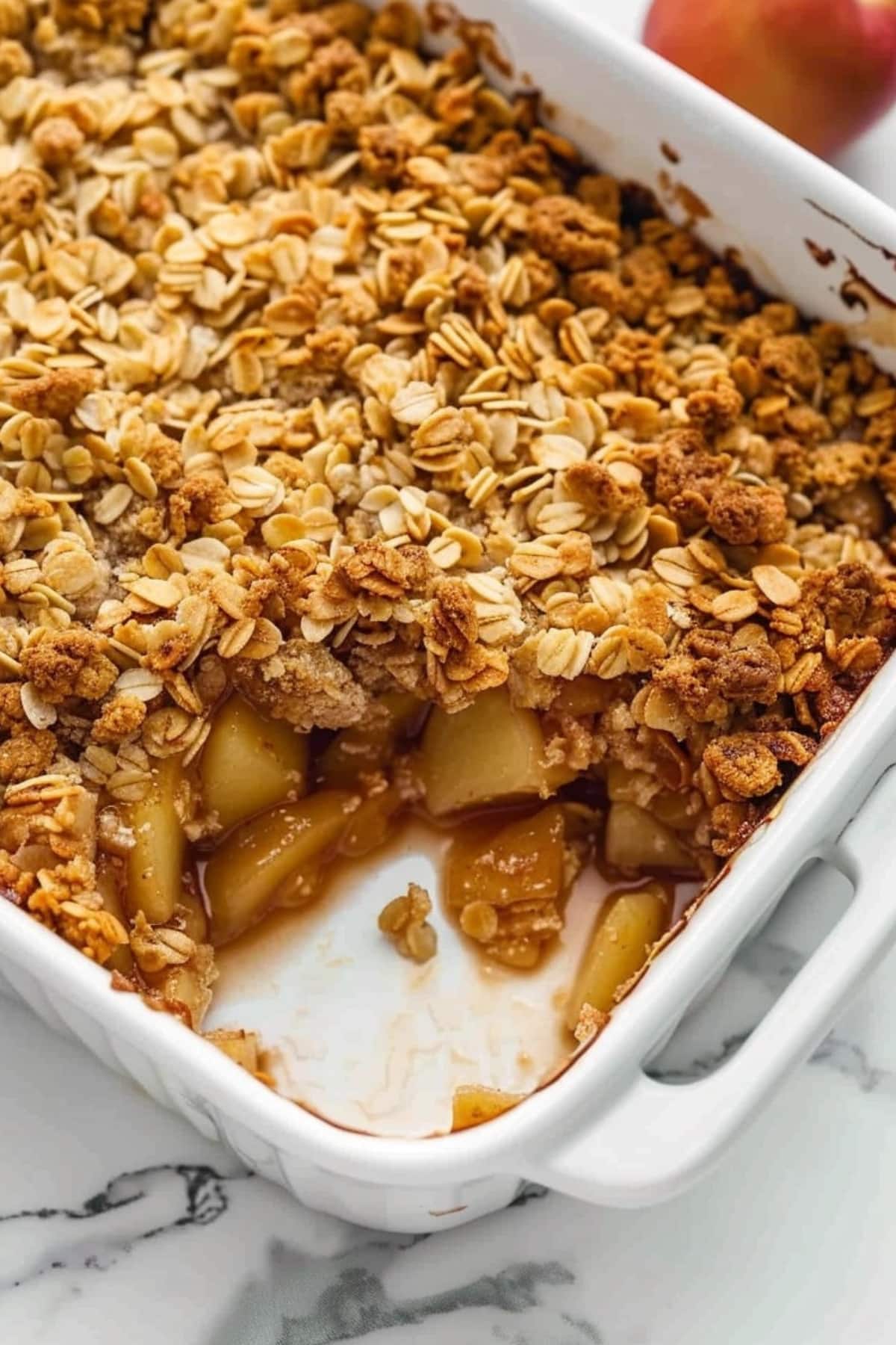 Pear crisp in a rectangular white baking dish topped with rolled oats.