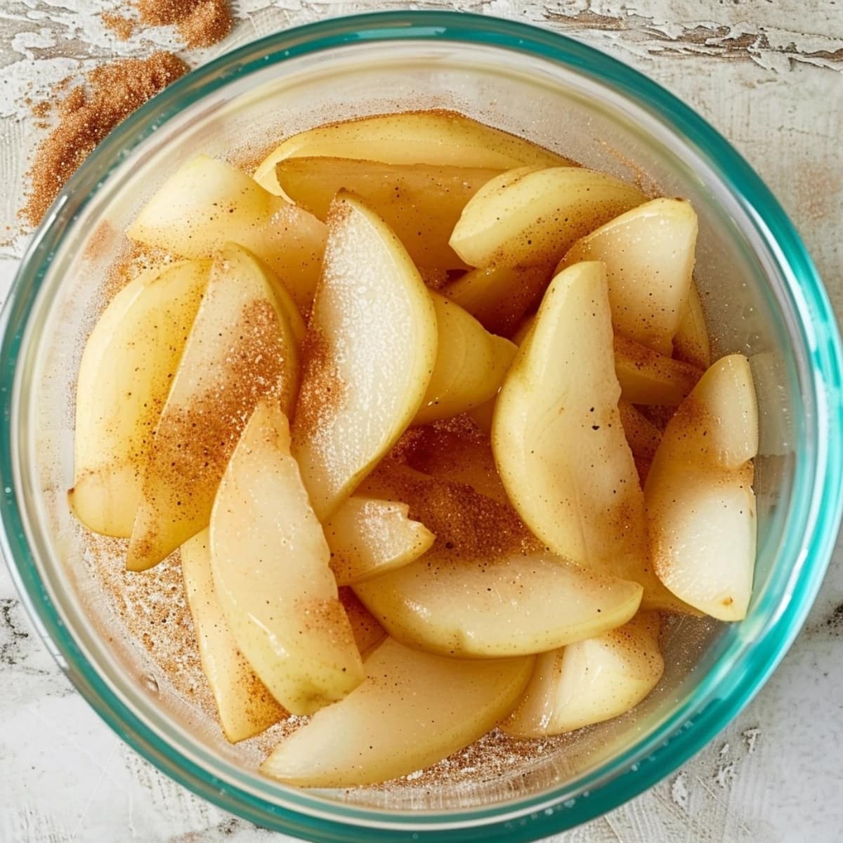Slices of pear in a clear bowl with cinnamon and brown sugar.