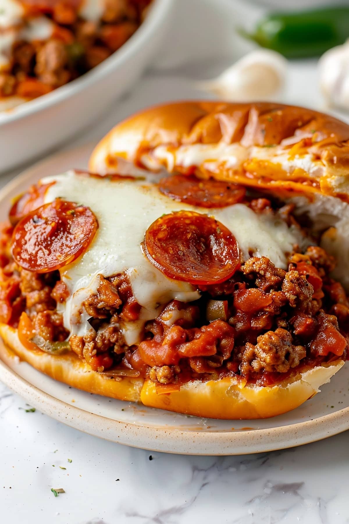 Deliciously messy pepperoni pizza sloppy joes with melted mozzarella cheese, Italian sausage and green bell peppers