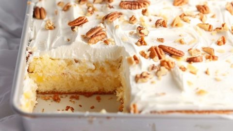 Pineapple sheet cake in a baking pan, portion slice missing.